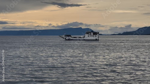 fishing boatWide Shot of a Ferry Ship Sailing on Lake Toba at Sunset with Samosir Island Hills in the Background in the fog