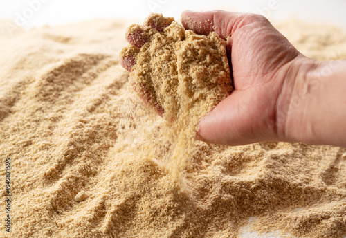 Hand pouring fresh rice bran powder on a pile