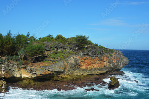 Majestic Ocean Waves Crashing Against Rugged Limestone Cliffs at Tropical Coastline