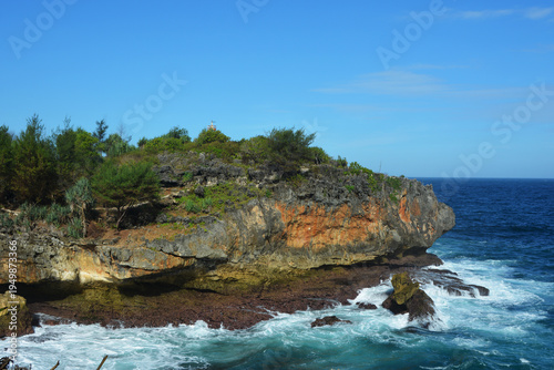 Majestic Ocean Waves Crashing Against Rugged Limestone Cliffs at Tropical Coastline