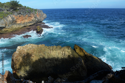 Majestic Ocean Waves Crashing Against Rugged Limestone Cliffs at Tropical Coastline