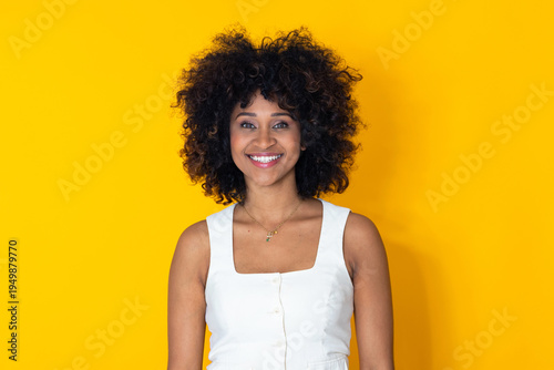 smiling young Latina woman with afro hair isolated on background