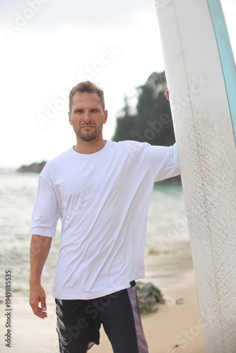 Casual Male Figure Wearing White T Shirt Standing Confidently With Surfboard At Seaside Scene