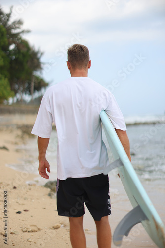 Casual Figure With Surfboard Under Arm Walking On Sand Along Coast Emphasizing Clothing And Product Display