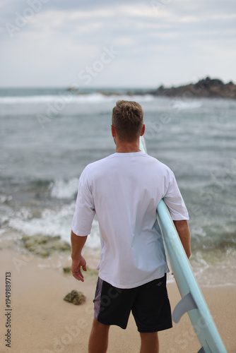 Man With Surfboard On Sands. Seaside Setting Featuring Man With Pastel Surfboard On Sandy Coast