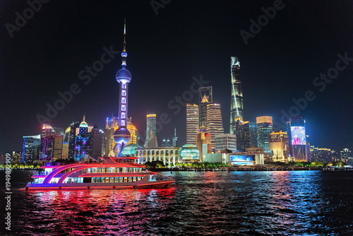 Night views of Shanghai's skyline with boat on the water. 