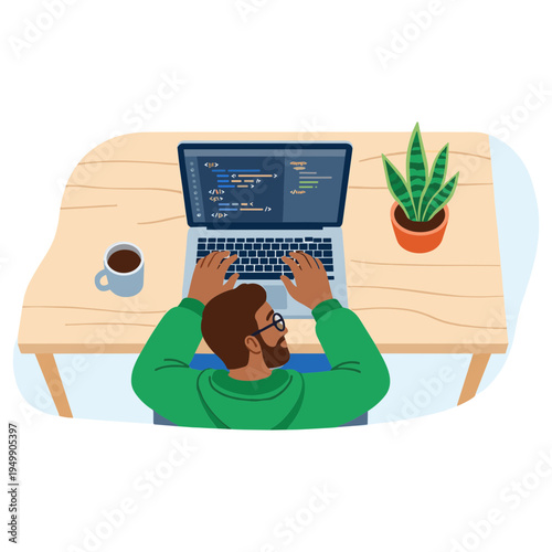 A man sits at a wooden desk working on a laptop with code on the screen next to a coffee cup and a potted plant.