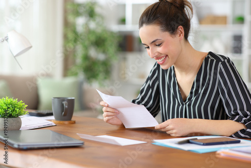 Happy self employed reading paper letter while working at home