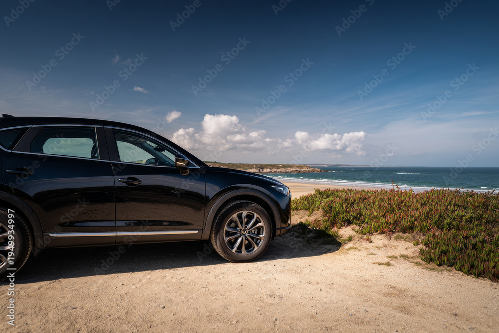 Naklejka premium SUV noir gare prÃ¨s dâ€™un paysage cÃ´tier vide, vue laterale complÃ¨te, no people, lumiÃ¨re ensoleillee, composition claire et equilibree, photographie automobile commerciale
