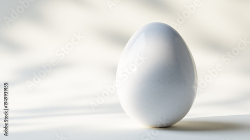 White ceramic egg on a table with soft spring Easter light and subtle bokeh