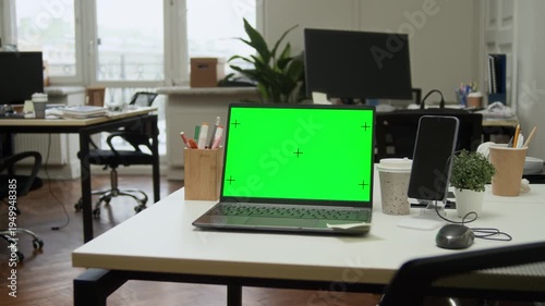 Medium shot of green chroma key copy space screen on wireless laptop on white table in modern office workspace, no people