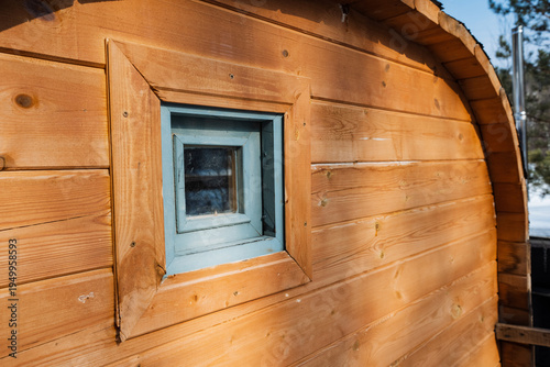 Cozy Rustic Retreat. Sunlit Nook In Charming Wooden Shelter. Inviting Small Blue Window In Rustic Wooden Cabin Scene. Picture Sunbathed Corner Of Quaint Wooden Shelter With Blue Window