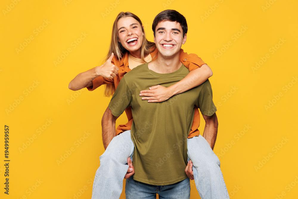 Fototapeta premium Young happy couple friends family man woman wear shirt casual clothes together giving piggyback ride to joyful, sit on back isolated on pastel plain light yellow background studio. Lifestyle concept.