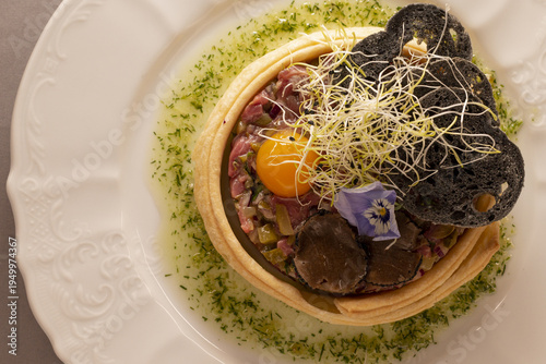 Close-up traditional steak tartare made with raw beef and egg yolk, beautifully plated in a restaurant, highlighting refined presentation and classic European cuisine.