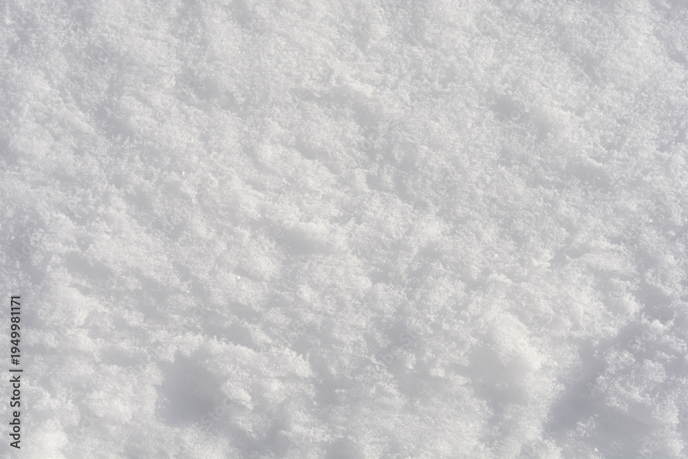Obraz premium Detailed top view of fresh white snow texture with small crystalline structures reflecting bright winter sunlight