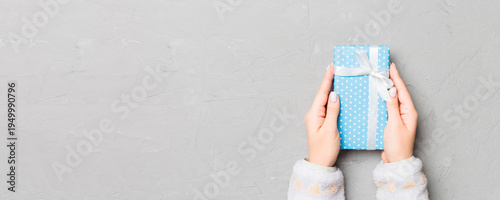 Wallpaper Mural Female hands holding present on grey cement background. Festive backdrop for Christmas holidays or other holiday . Flat lay style top view with copy space Torontodigital.ca