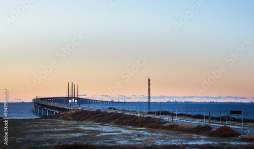 Sunset view from Lernacken of the Öresund Bridge curving over calm sea conveys infrastructure concept. Distant city of Copenhagen and coastal road in winter landscape between Sweden and Denmark