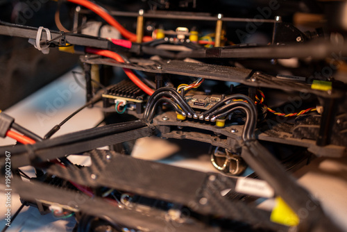 Stack of 10-inch FPV drones with visible wiring and carbon frames, arranged in a workshop setting.