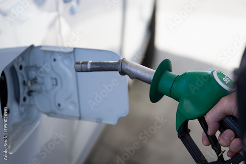 Фотография man refilling car with e20 biofuel and 95 octane gasoline at gas station, close
