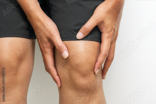 Foto Hand holding injured left knee on white background with copy space for advertising use