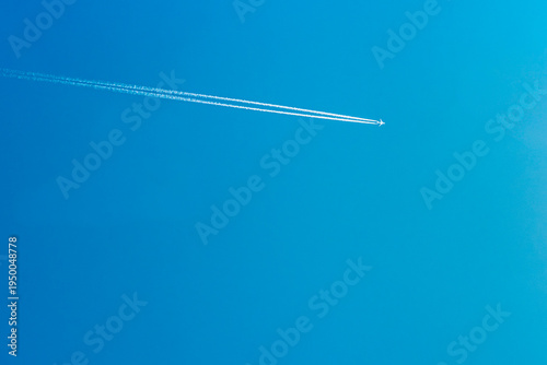Bild auf Leinwand Airplane flying high in a clear blue sky, leaving a white contrail behind, showc