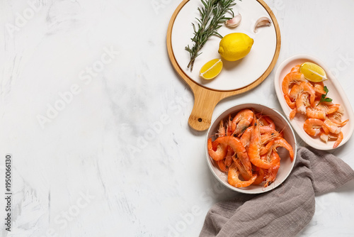Bowls of tasty boiled shrimps with lemon and rosemary on white background