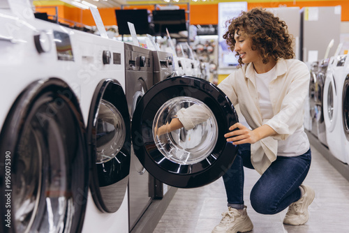Obraz na plátně Woman shopping for new washing machine in appliance store, inspecting features f