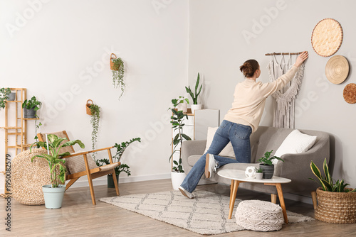 Young woman hanging tapestr...