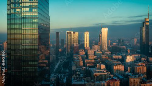 Warsaw, Poland - 06 February 2023: Aerial view of a modern cityscape with towering skyscrapers gleaming in the sunlight, casting long shadows across the bustling city below.