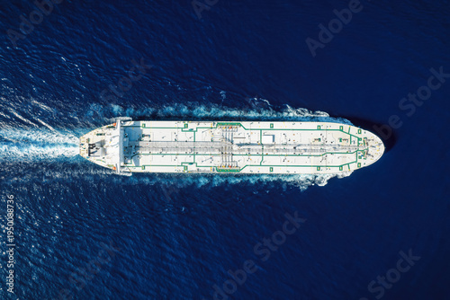 High aerial top view of a crude oil tanker traveling with speed over the ocean with copy space