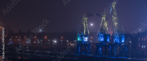 Bild auf Leinwand THE LANDSCAPE OF THE PORT CITY - Beautifully lit old historic port cranes in Sz