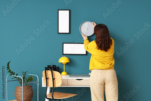 Young woman hanging clock o...