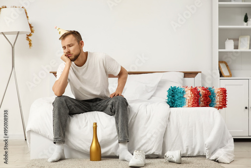 Young man with hangover sit...