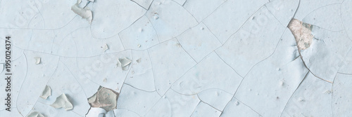 Peeling paint on the wall. Old concrete wall with cracked flaking paint. Weathered rough painted surface with patterns of cracks and peeling. Grunge texture for background and design. High resolution.