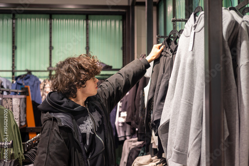 Fotografía Young Teenage Boy Shopping for Black Hoodie in Clothing Store - Gen Z Streetwear Fashion and Retail