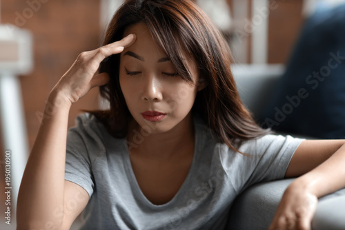 Sad young Asian woman sitti...