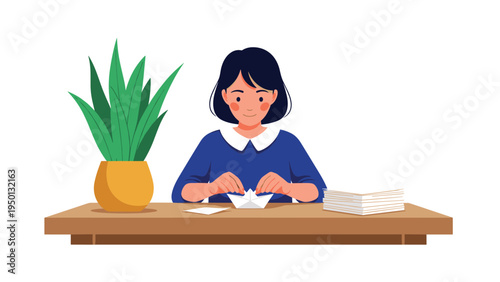 Young woman sitting at a wooden table and carefully folding a white paper boat with a plant and stack of paper nearby.