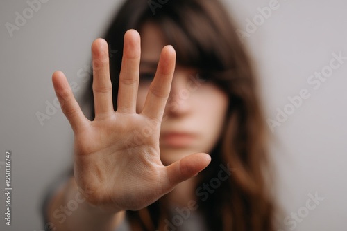 Woman with outstretched hand, palm facing camera, in a gesture of stop or hesitation