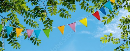 Colorful Pennant Flags Flutter Amidst Green Leaves Against a Clear Blue Sky