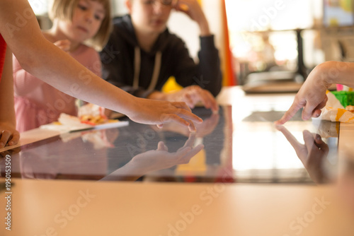 Children fingers touching an interactive touchscreen surface, exploring digital content through play and learning.