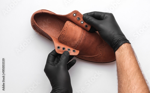Professional shoe care. Shoemaker holding  leather boots on a white background