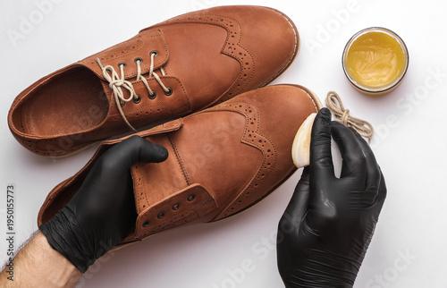 Shoemaker applies shoe polish to leather shoes on a white background