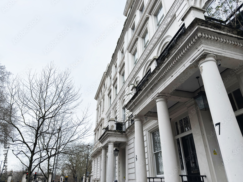 Fototapeta premium Elegant white terrace house in London with columns and balconies on a cloudy day