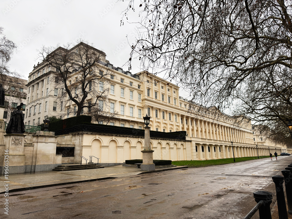 Fototapeta premium Elegant neoclassical Carlton House Terrace building along a tree-lined street in London, UK, during cloudy day with promenade
