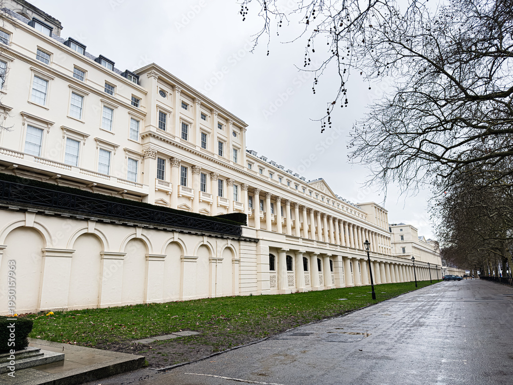 Fototapeta premium London Carlton House Terrace architectural facade along a long cream building with arches and bare trees on a quiet street