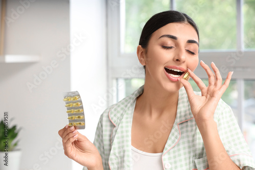 Young woman taking vitamin ...