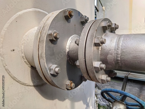 Industrial steel pipe flange connection with bolts and nuts on a pressurized storage tank in a chemical processing plant or refinery factory.