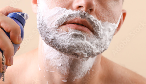 Man's face with shaving foam on a beige background