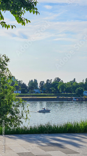 Small Motorboat on Calm River With Green Riverside Landscape