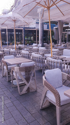 Elegant Outdoor Restaurant Terrace With Woven Chairs and Fringe Umbrellas